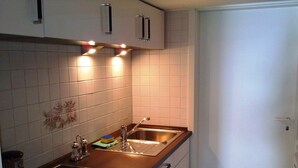 A modern kitchen with white tiles, stainless steel appliances, and a wooden countertop.