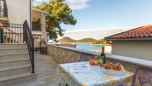Ein Balkon mit Tisch für zwei Personen, mit Blick auf ein Gewässer und Hügel.