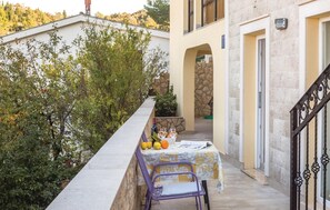 A balcony with a table set for two, a chair, and a stone wall.