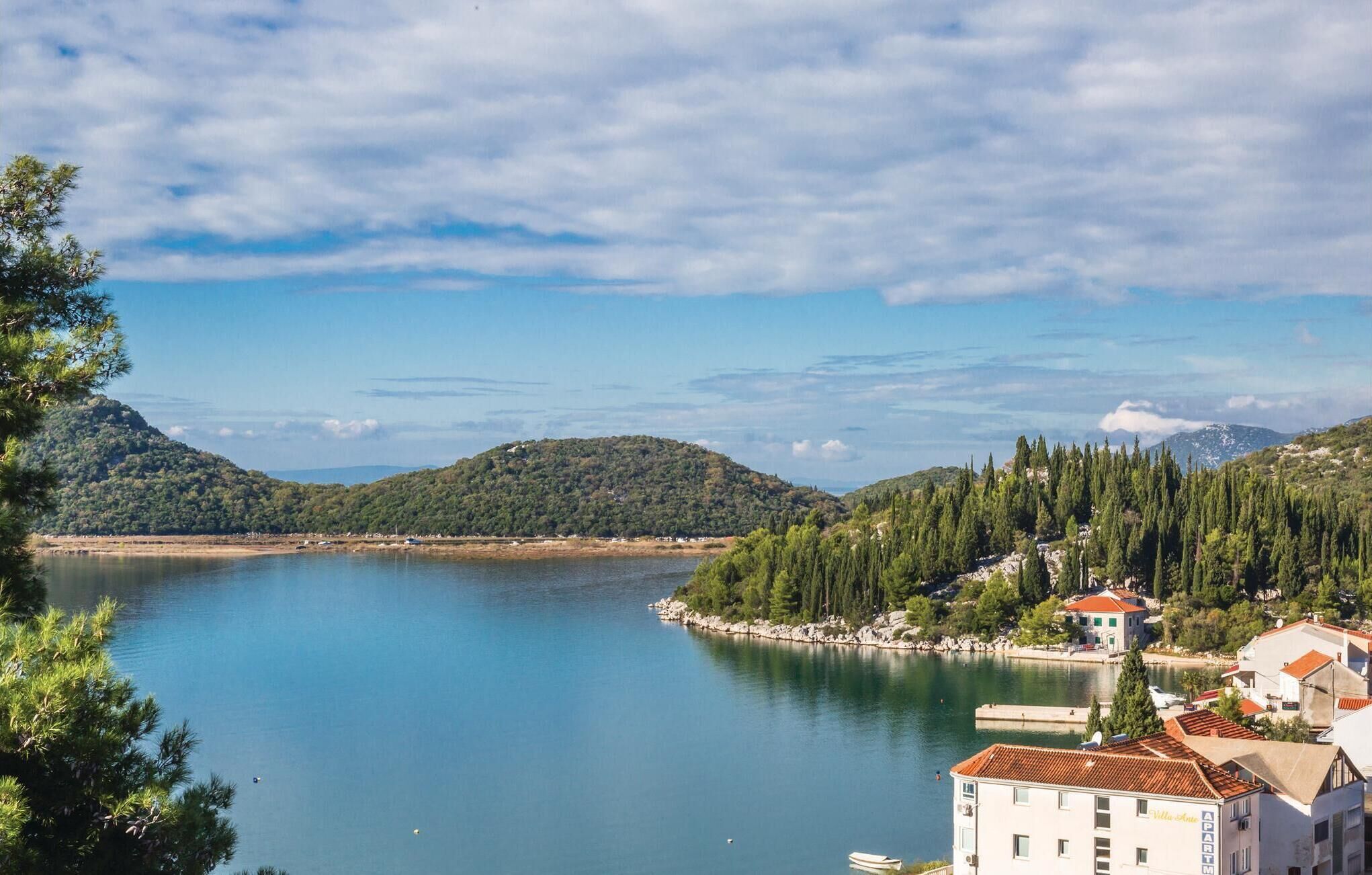 Un pueblo costero con un lago, rodeado de colinas y bosques frondosos.