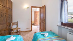 A hotel room with two beds, a wooden wardrobe, a chair, a window with a view, and a light fixture. - 2 bedroom nice apartment in Joppolo VV (Joppolo VV)