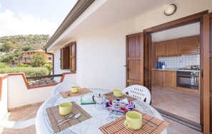 A round table with a white marble top, surrounded by four yellow cups and a tray with a Union Jack design, set on a balcony with a view of a hillside and neighboring buildings. - 2 bedroom nice apartment in Joppolo VV (Joppolo VV)