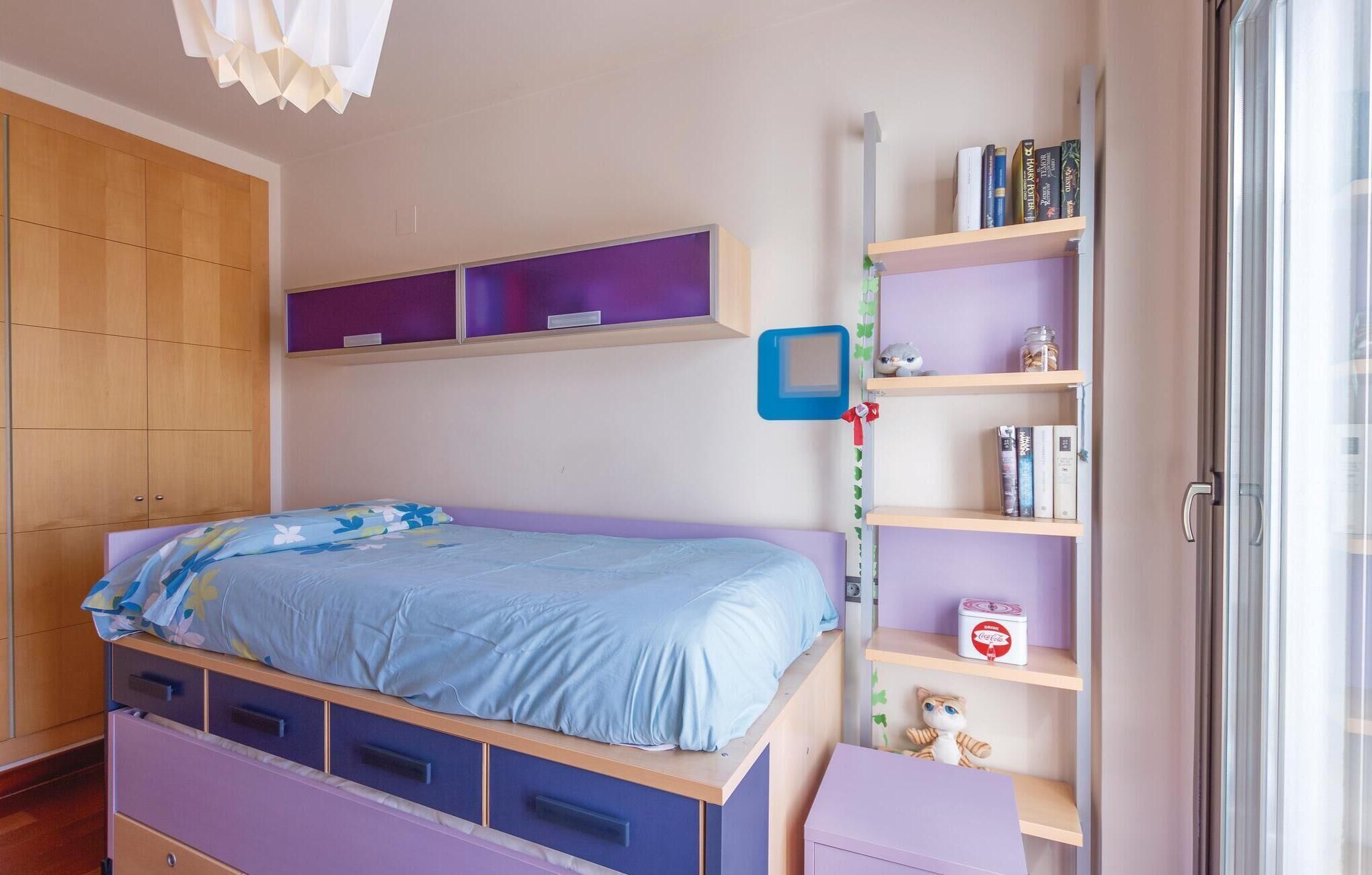 Une chambre à coucher avec un lit, une armoire, une bibliothèque et une fenêtre.