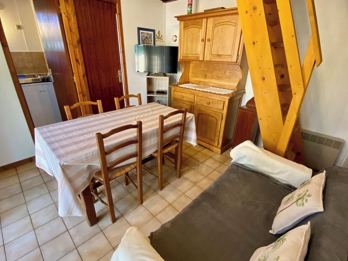 Un coin repas avec une table et des chaises, une cuisine avec des meubles en bois et un canapé avec des coussins.