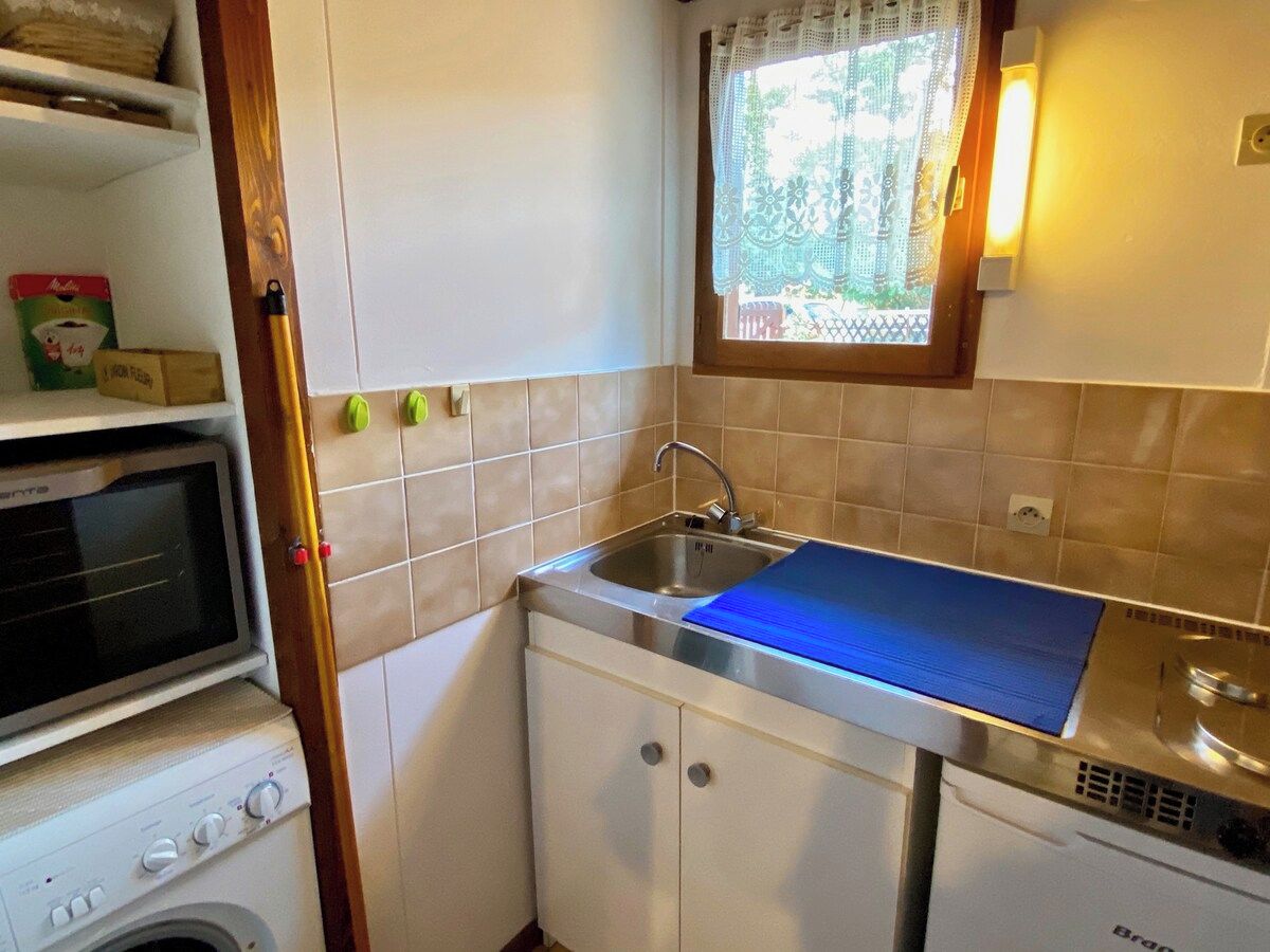 Une cuisine compacte équipée d’un évier, d’un four à micro-ondes et d’un lave-linge.