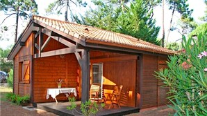 Une cabane en bois dotée d’un porche abrité, d’une table et de chaises.