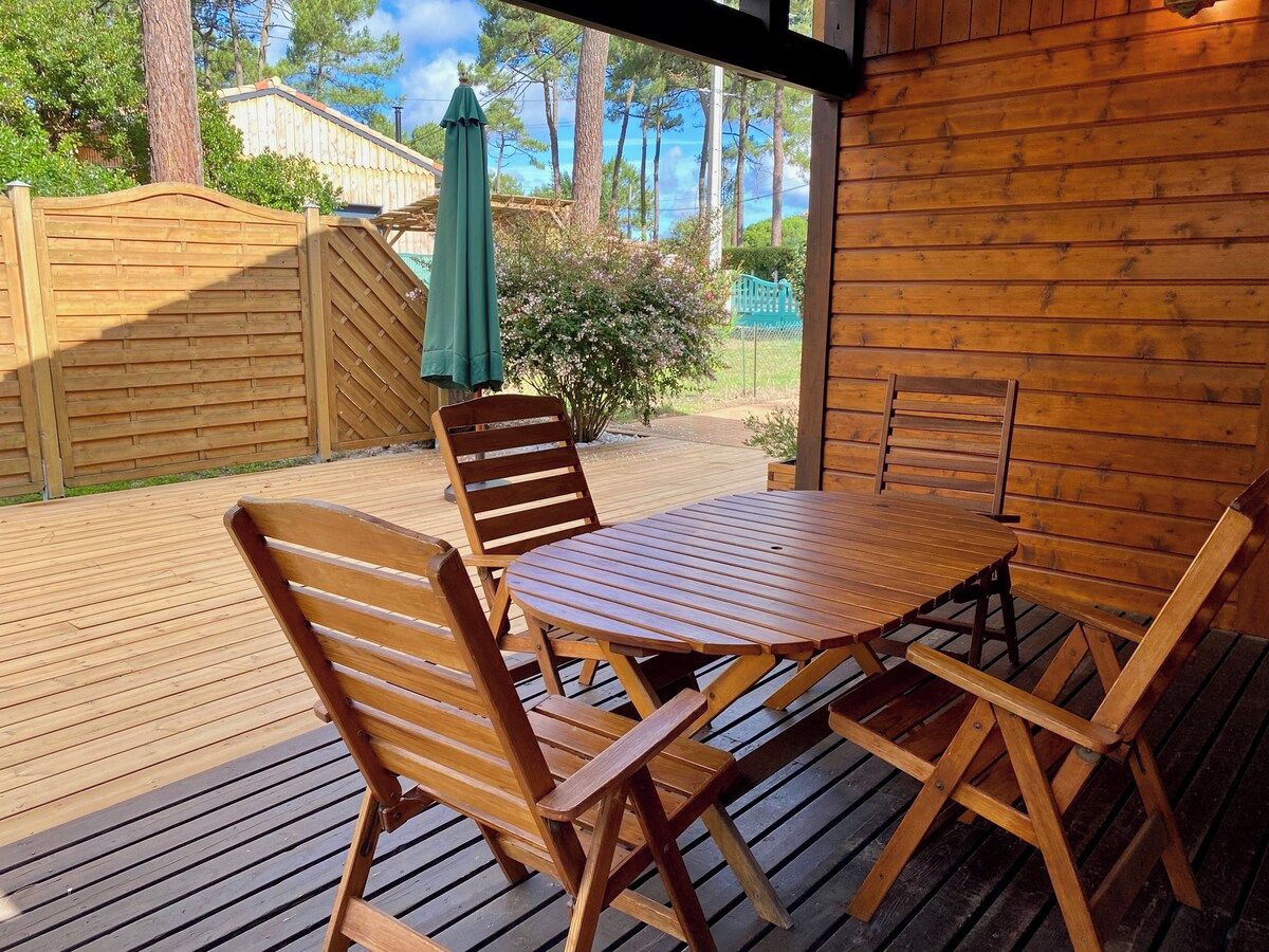 A wooden deck with a table and chairs, a green umbrella, and a wooden fence.
