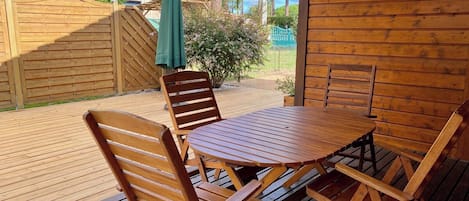A wooden deck with a table and chairs, a green umbrella, and a wooden fence.