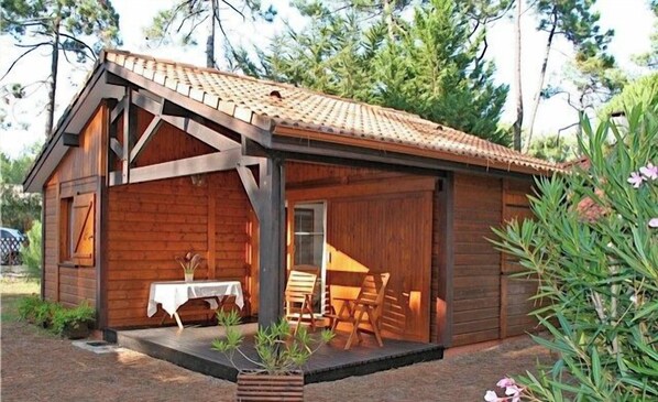 A wooden cabin with a covered porch, a table, and chairs.