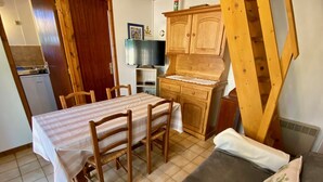 Une cuisine compacte comprenant une table et des chaises, un meuble en bois et un petit réfrigérateur.