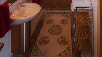 Baño con lavamanos, espejo y armarios de madera.