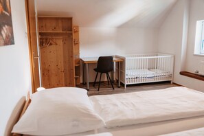 A room with a crib, a desk, and a chair.
