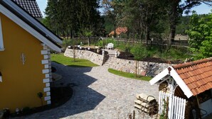 A stone pathway leading to a stone wall with a wooden fence and a small garden area with a bench and a table. - Small yellow villa in Masuria (apartment WEST in the attic) (Swieta Lipka,)