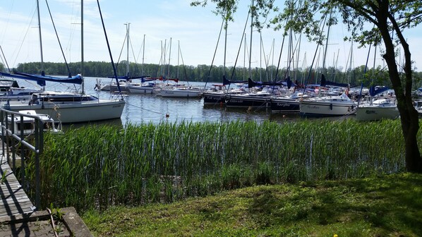 A marina with multiple boats docked, surrounded by greenery and a clear sky. - Small yellow villa in Masuria (apartment WEST in the attic) (Swieta Lipka,)