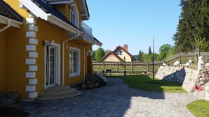 A yellow building with a stone pathway leading to a wooden fence. - Small yellow villa in Masuria (apartment WEST in the attic) (Swieta Lipka,)