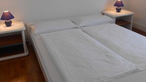Ein Doppelbett mit weißer Bettwäsche, zwei Nachttische mit Lampen und ein Holzboden.