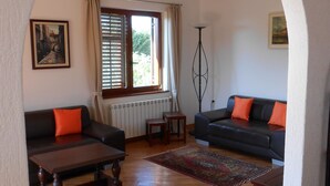 Ein Wohnzimmer mit zwei Sofas, einem Couchtisch, einer Stehlampe und einem Fenster mit Vorhängen.