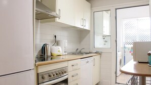 Una cocina compacta con armarios blancos, estufa y lavaplatos.