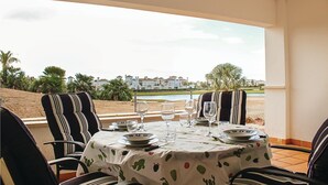 Mesa para dos personas con vista a un campo de golf y edificios al fondo.