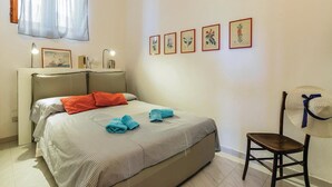 Una camera da letto ordinata con un letto, una sedia e opere d'arte appese al muro.