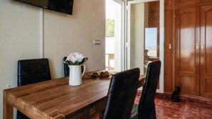 A dining area with a wooden table, two chairs, a white pitcher with flowers, and a television mounted on the wall. - Beach front apartment in Cartagena (Cartagena)