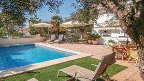 A swimming pool with lounge chairs and umbrellas, surrounded by a patio area with potted plants and a view of a building. - Beach front apartment in Cartagena (Cartagena)