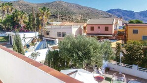 A terrace with a view of a mountain, a pool, and buildings with a tiled roof. - Beach front apartment in Cartagena (Cartagena)
