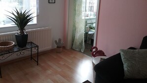 A living room with a potted plant, a small table, a flamingo decoration, and a view through a curtain to a dining area. - Holiday house, Martha``am Szczecin Lagoon / Meck / Pom / Ueckermünde-Bellin (Ueckermünde)