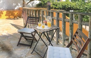 Un tavolo di legno con una sedia imbottita e un'altra sedia con cuscino, su un patio in pietra.