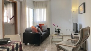Una sala de estar con un sofá, una mesa de centro, un televisor y una silla.