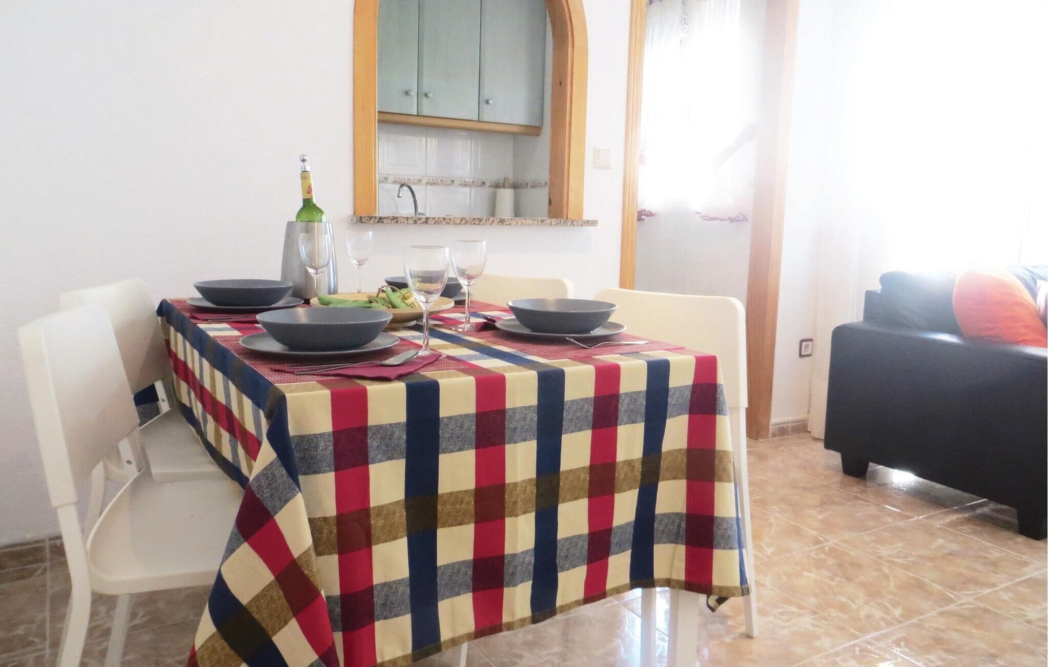 A dining area with a checkered tablecloth, a bottle, and glasses set for a meal.