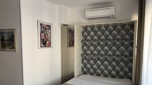 Habitación de hotel con cama, unidad de aire acondicionado y obras de arte en las paredes.