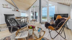 Ein geräumiges Wohnzimmer mit Meerblick, einem Essbereich und einer Sitzecke mit Fernseher.