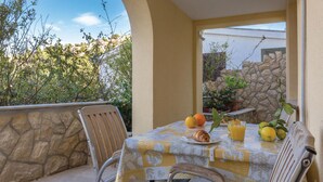 A table set with breakfast items on an outdoor patio with stone walls and a view of greenery. - Gorgeous apartment in Blace with WiFi (Blace)