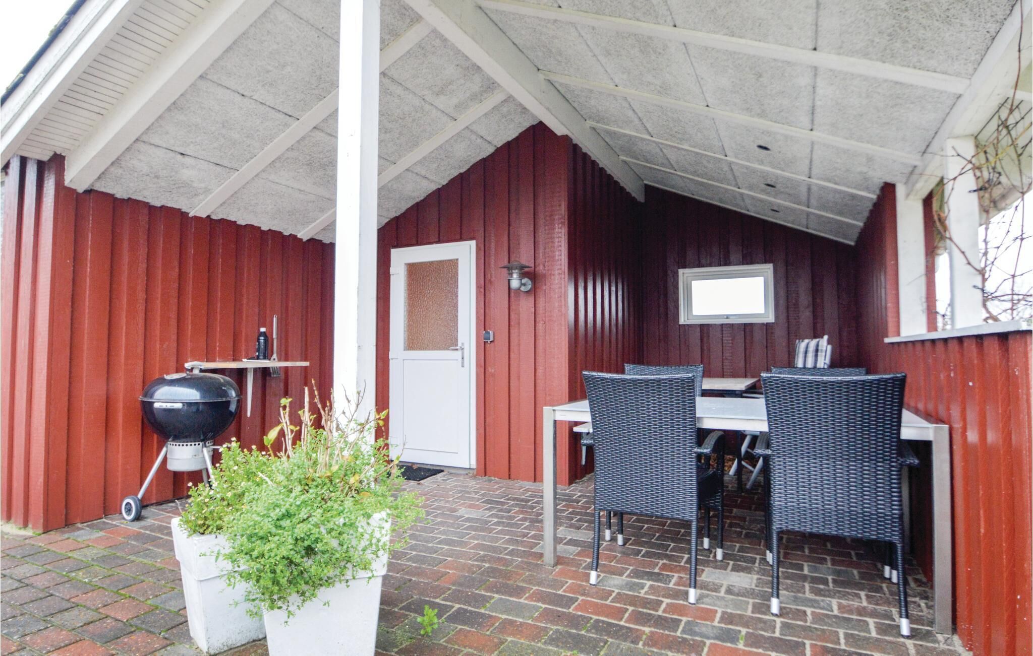A covered patio area with a brick floor, a grill, and outdoor furniture.