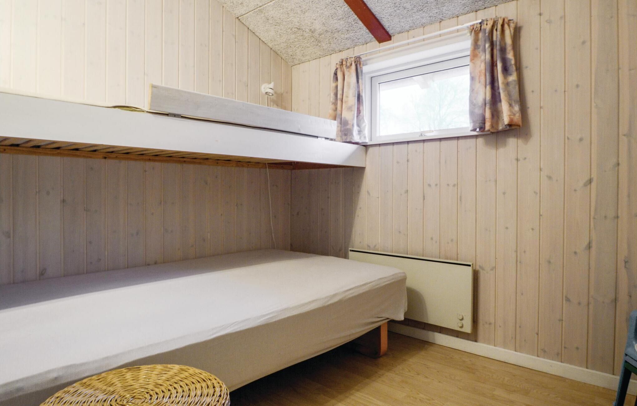 Habitación con literas, paredes de madera y ventana con cortinas.