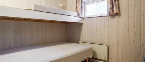 Habitación con literas, paredes de madera y ventana con cortinas.