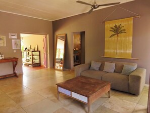 Ein Wohnzimmer mit einer Couch, einem Couchtisch, einem Deckenventilator und einem großen Gemälde.