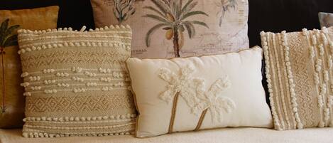 A sofa with multiple cushions, a woven throw blanket, and a wooden frame.