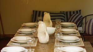 Een eettafel gedekt met borden, glazen en een karaf, met daarboven een hanglamp.