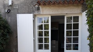 A patio with a table and chairs, a white door with glass panels, and a small step leading to a covered area. - LAST MINUTE Studio N ° 5 BC (Cavalaire-sur-Mer)