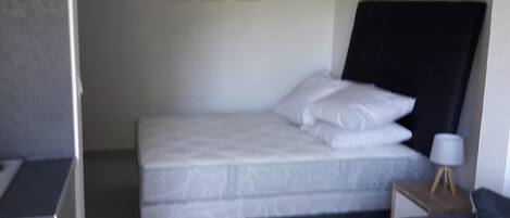 A compact bedroom with a single bed, a small bedside table with a lamp, and a sofa.