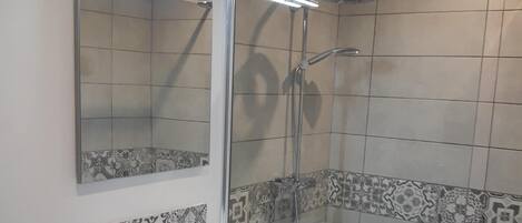 A bathroom with a white sink, mirror, and shower.