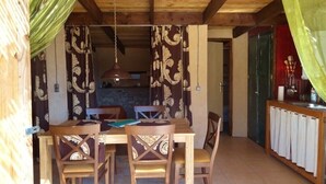 Un coin repas avec une table et des chaises en bois, un luminaire suspendu et des rideaux.