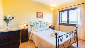 A bedroom with a bed, bedside tables, a nightstand, a window with a view, and a picture on the wall.