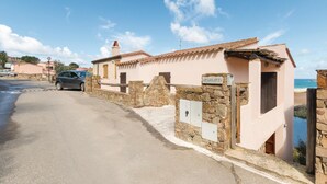 A coastal building with a stone wall and a car parked in front.