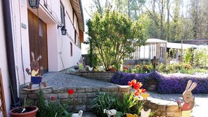 Un jardín con diversas figuritas de animales, un muro de piedra y un edificio con puerta de madera.