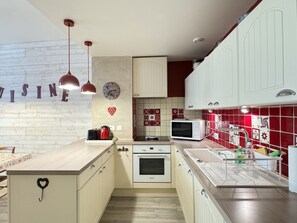 A compact kitchen with white cabinets, a wooden countertop, a microwave, and a sink. - Centre Cauterets, appartement 72m2 pr 7 personnes (Cauterets)