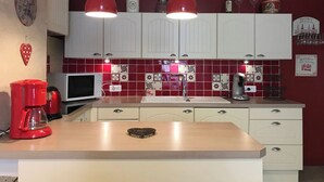 A kitchen with white cabinets, a microwave, a coffee maker, and a red pendant light. - Centre Cauterets, appartement 72m2 pr 7 personnes (Cauterets)