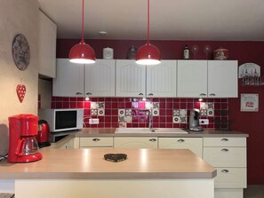 A kitchen with white cabinets, a microwave, a coffee maker, and a red pendant light. - Centre Cauterets, appartement 72m2 pr 7 personnes (Cauterets)